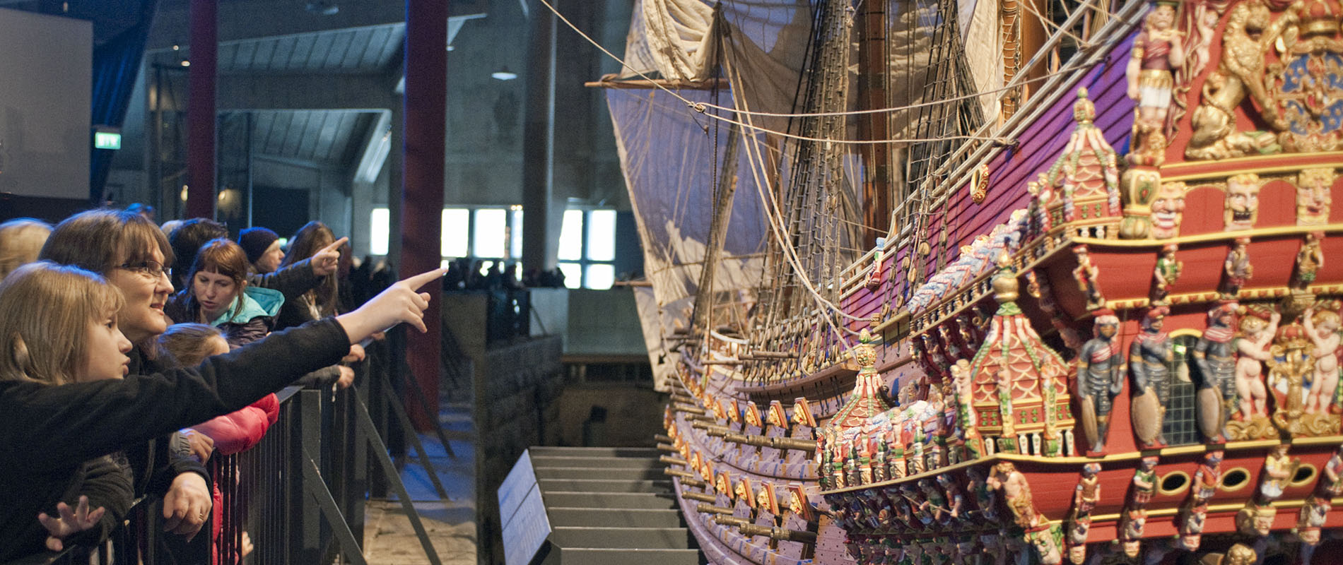 Besökare på museet vid färgglad modell av skeppet Vasa.